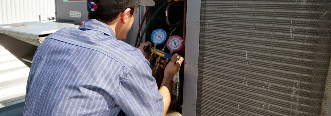 HVAC technician servicing a condenser unit in Carl Junction